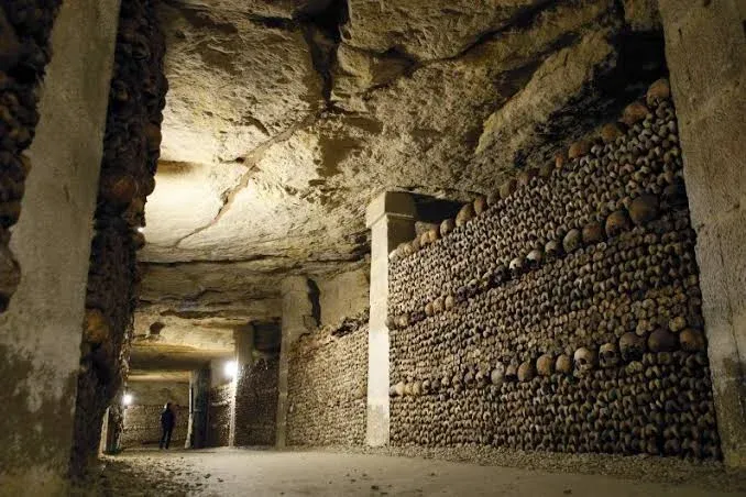 Mur d'ossements et de crânes alignés dans une galerie de l'ossuaire des Catacombes de Paris