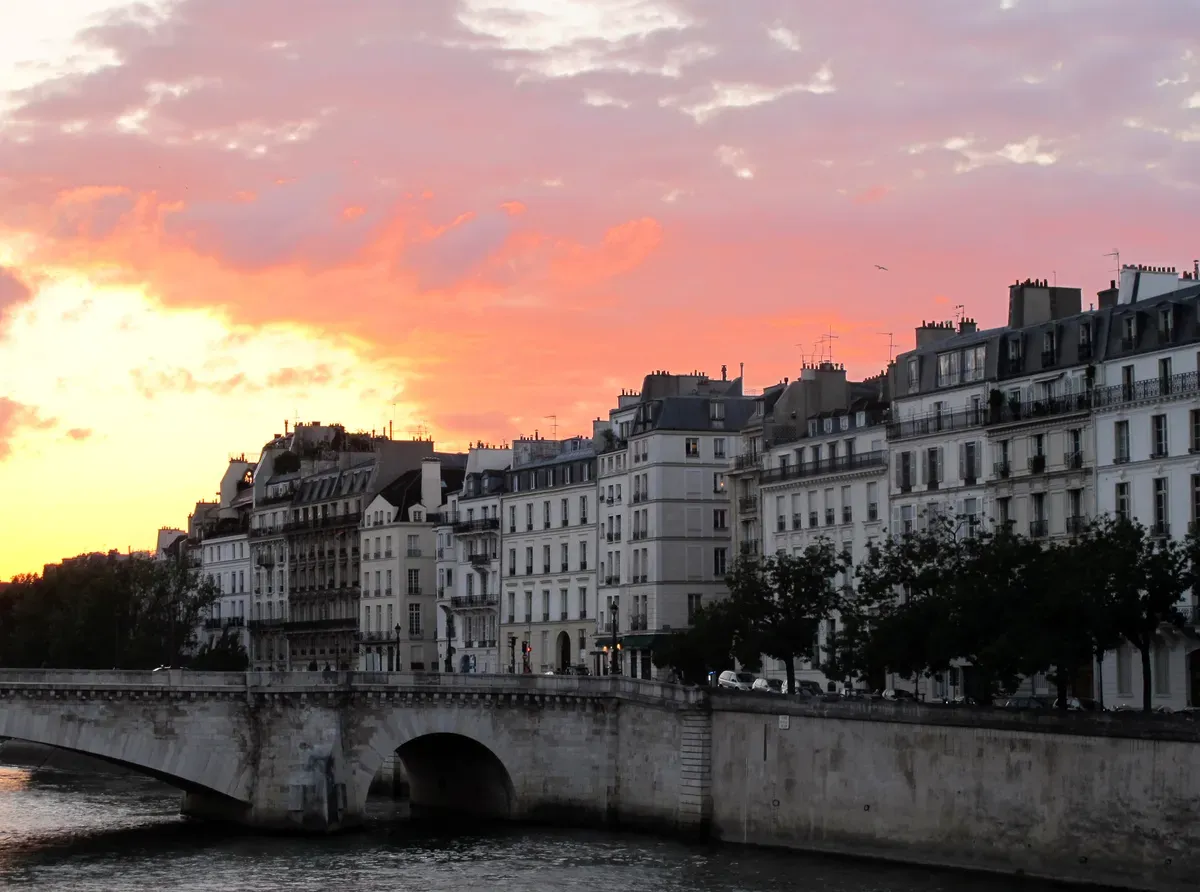 Le pont de la Tournelle et les immeubles du quai d'Orléans, sur l'île Saint-Louis, sous un ciel de coucher de soleil rose et orange