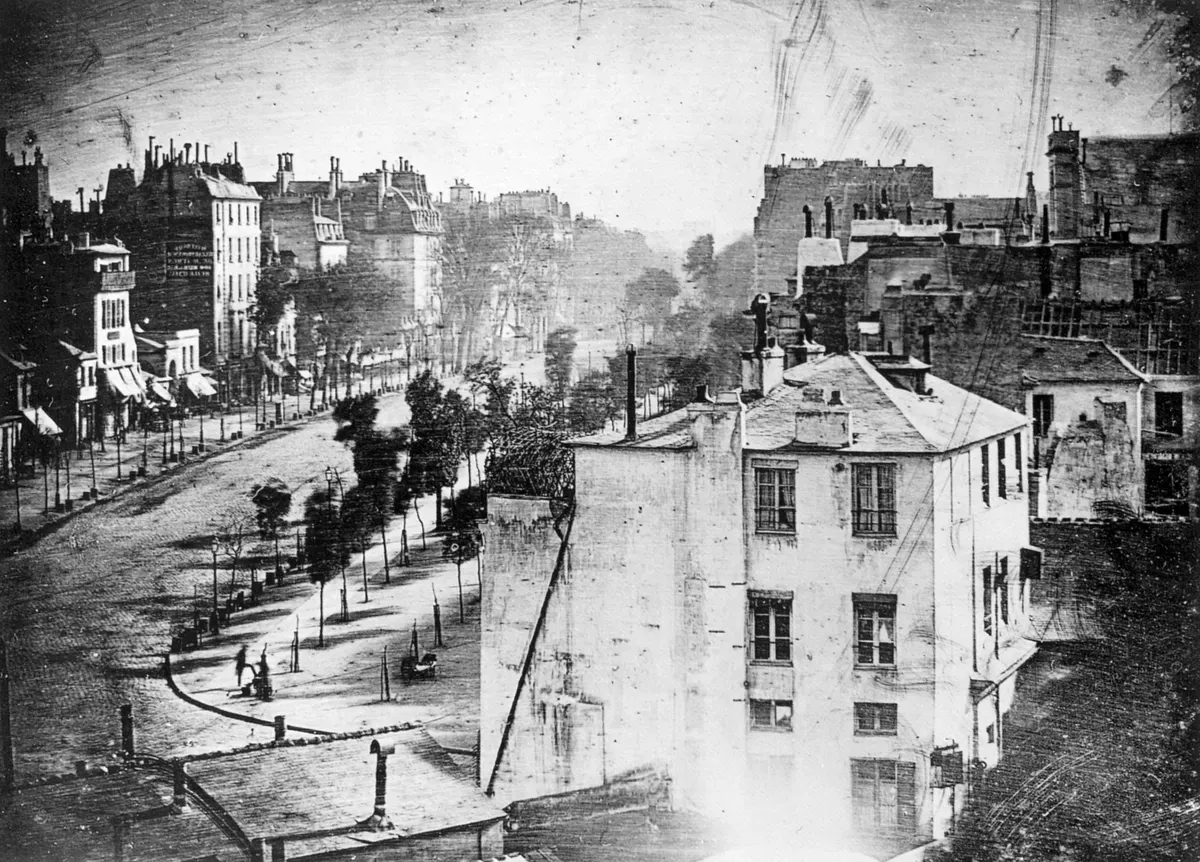 Le boulevard du Temple vu d'en haut, chaussée déserte, arbres et immeubles, avec une silhouette minuscule au coin d'une rue en bas à gauche