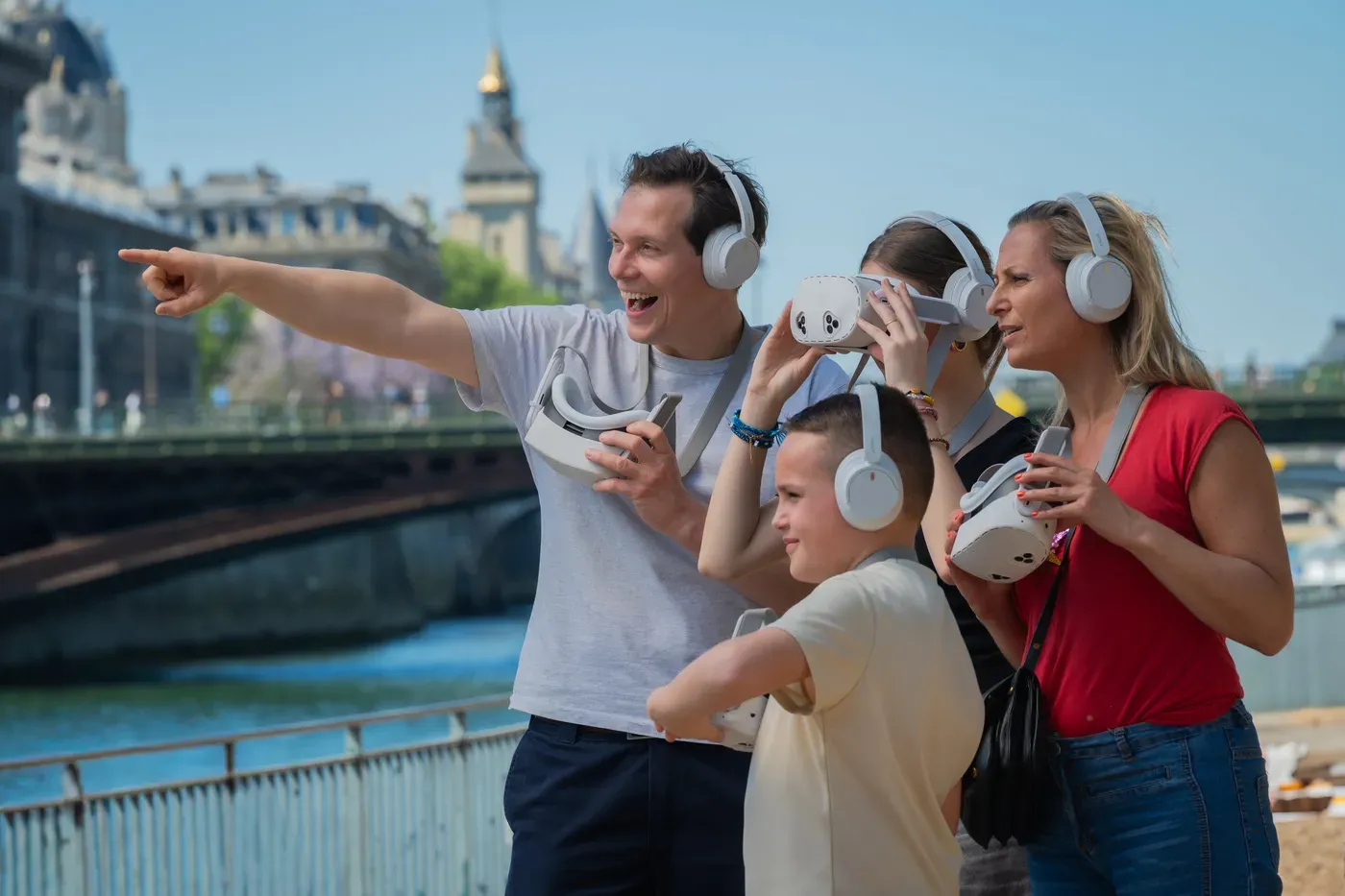 A guide points out a detail of the landscape to a boy and a teenage girl wearing Timescope binoculars, on the banks of the Seine