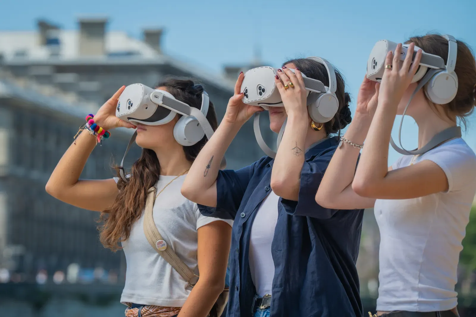 Tres compañeras levantan juntas los prismáticos de realidad virtual Timescope a orillas del Sena, en París