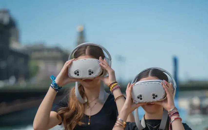 Two visitors of The Origins of Paris look at the Seine through virtual-reality binoculars