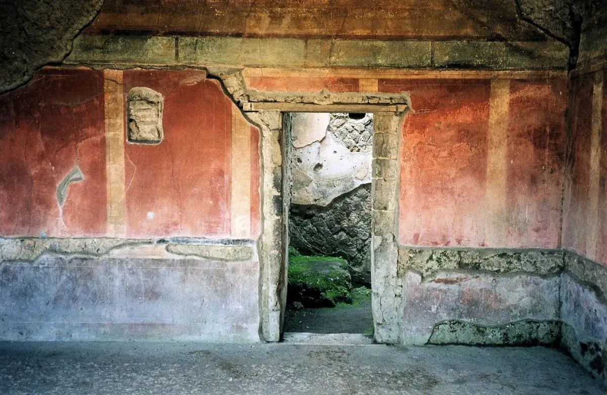 Ruines de Pompéi : fresques rouges et porte ouverte sur une pièce effondrée
