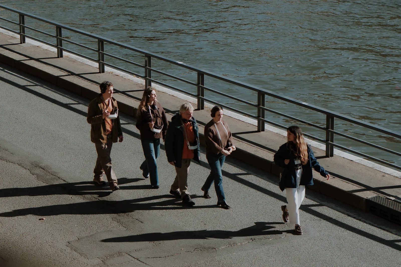 Un groupe de visiteurs des Origines de Paris marche le long de la Seine avec un guide, jumelles de réalité virtuelle en main