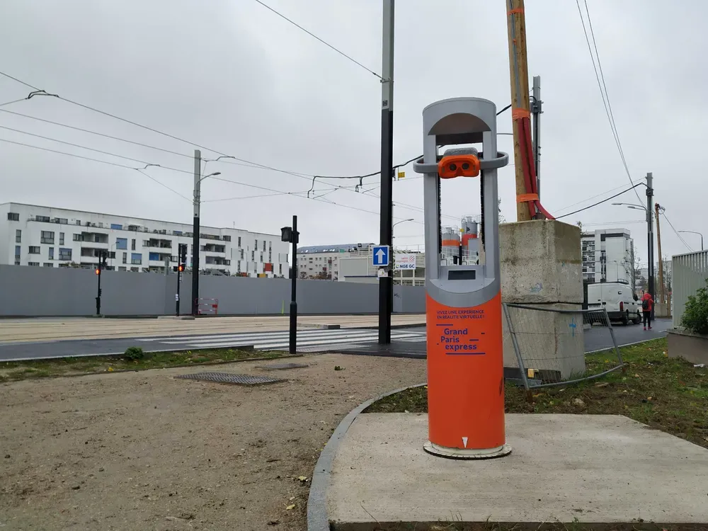 La cabina Timescope con los colores del Grand Paris Express, junto a las obras