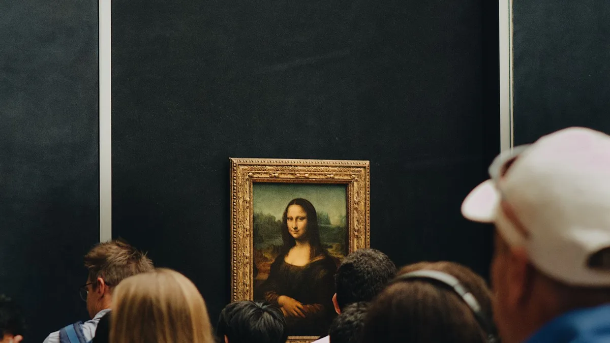 La Joconde vue par-dessus une foule de visiteurs de dos, dans la salle bondée du Louvre
