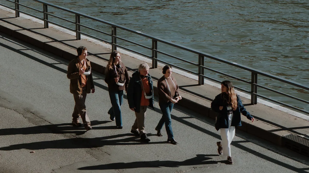 Promeneurs sur les berges de la Seine sous les feuillages roux d'automne, avec un pont de Paris en arrière-plan