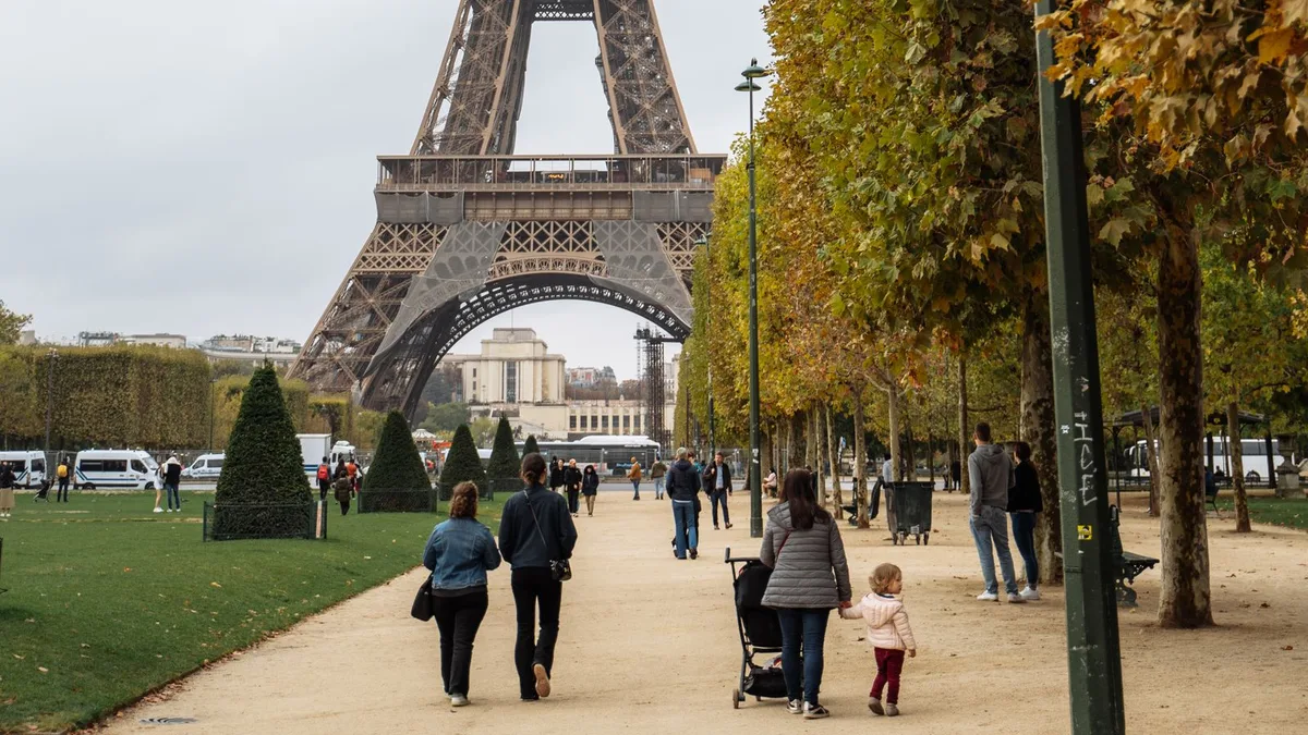 Familles en promenade sur le Champ-de-Mars aux couleurs d'automne, la Tour Eiffel en arrière-plan